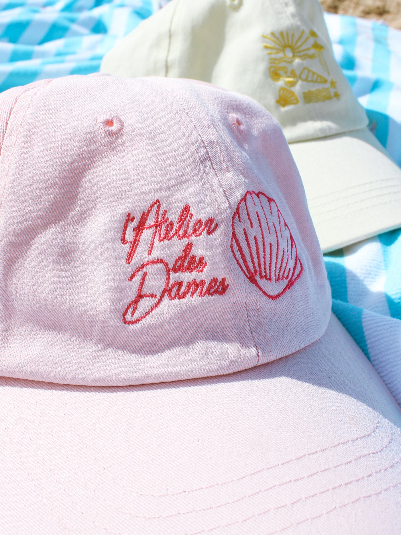 casquettes rose et jaune à motifs sur serviette de plage - l'atelier des dames x broders cap